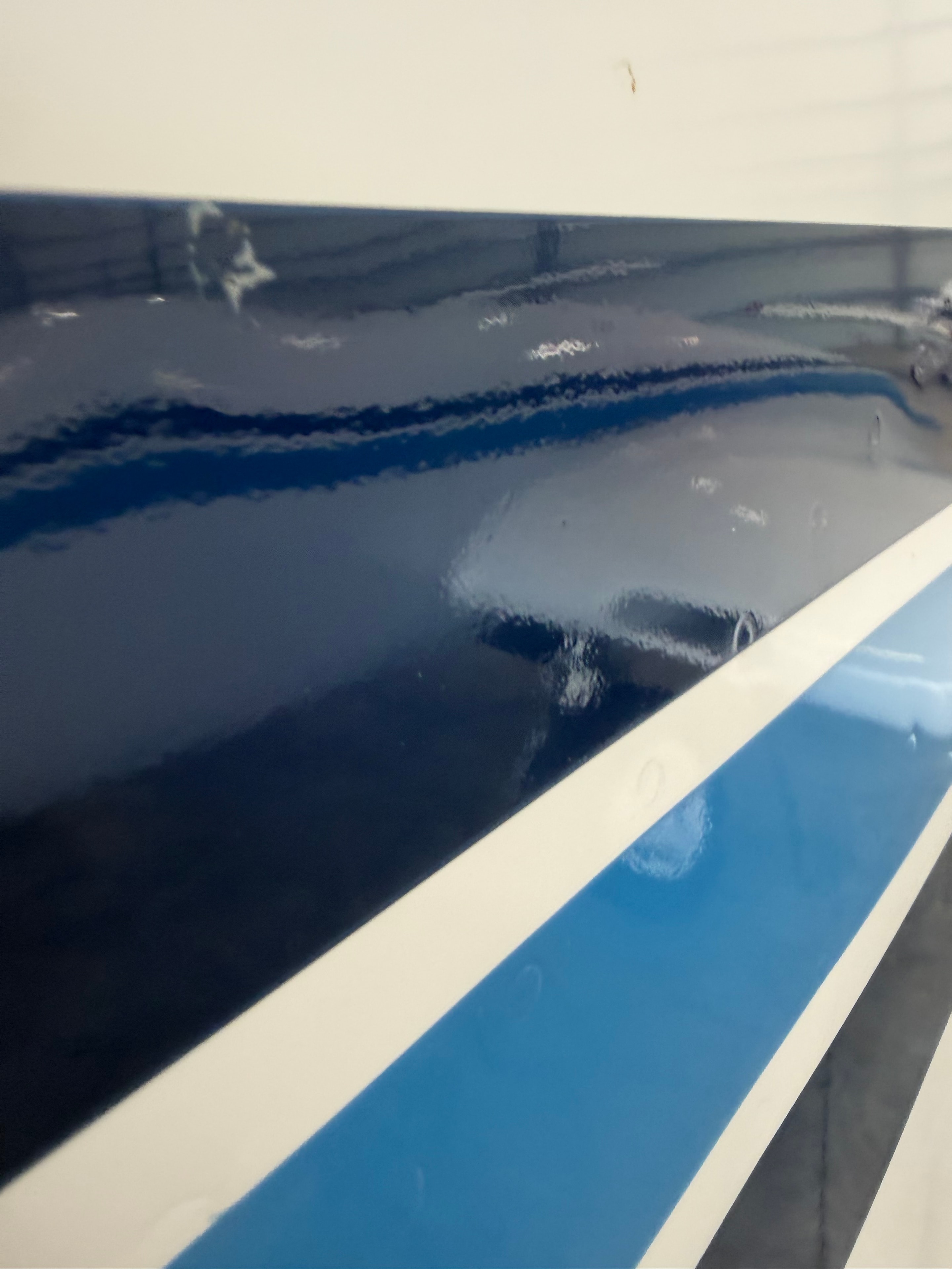 Glossy dark blue and light blue paint stripes on aircraft fuselage