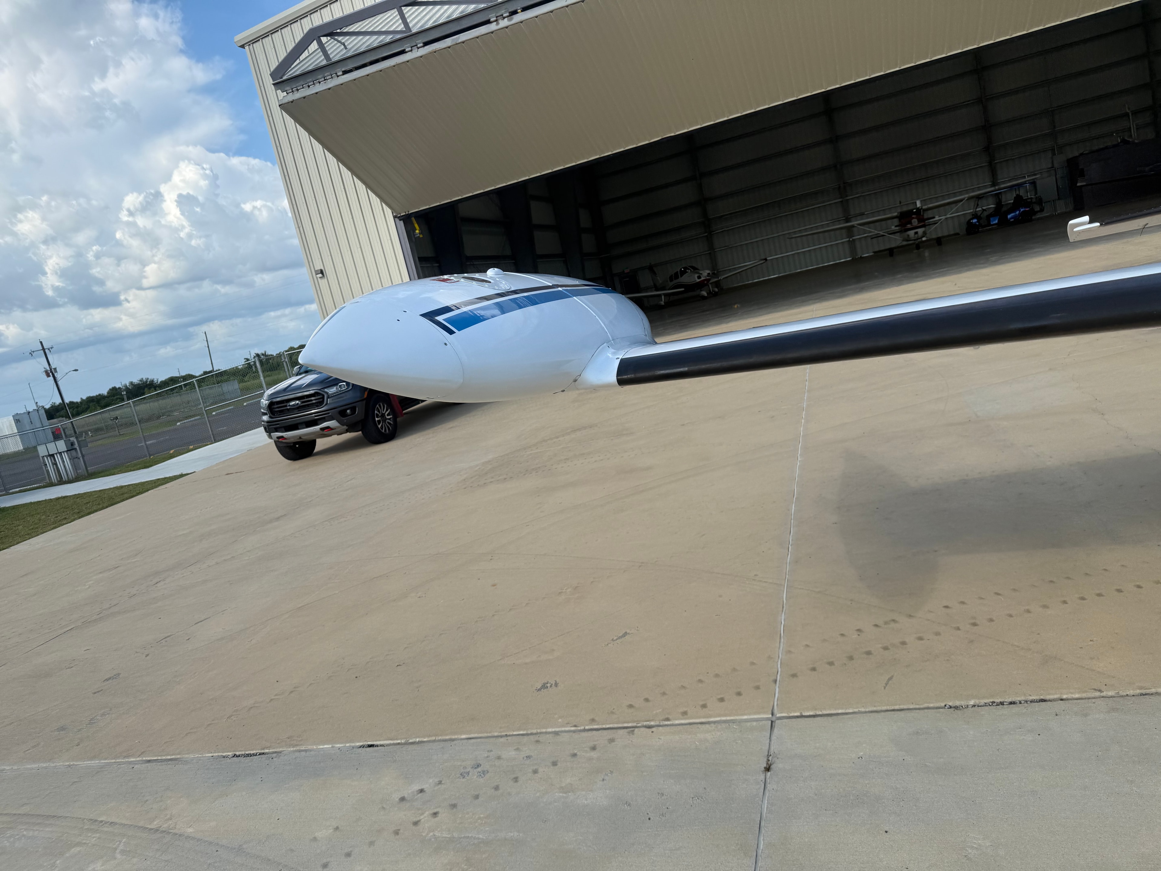Aircraft wingtip and fuselage outside hangar with service truck