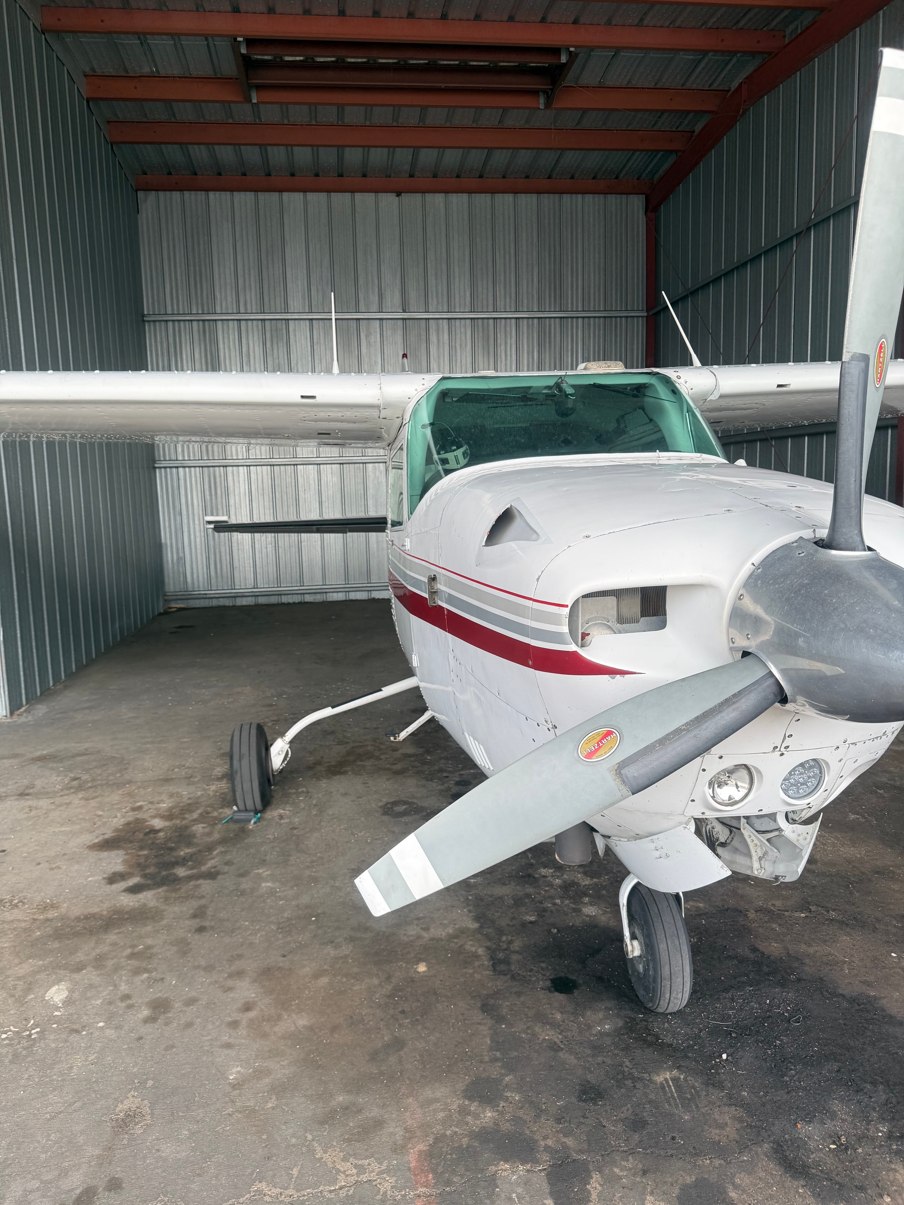 White and red Cessna aircraft parked inside a hangar, front view